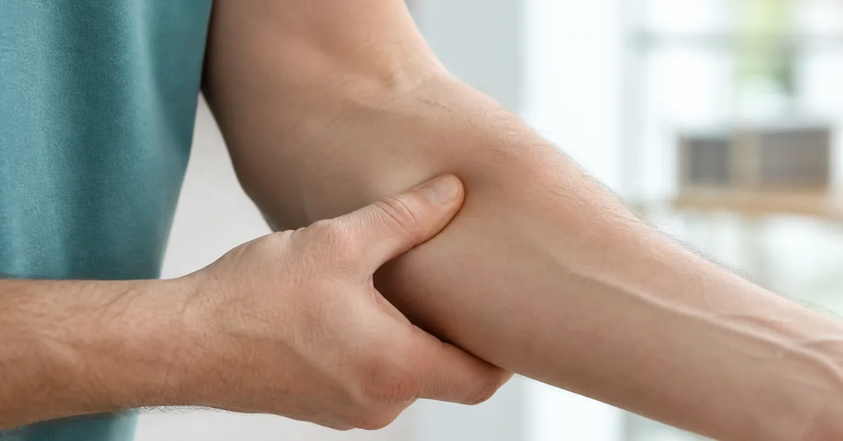 Person umfasst mit der anderen Hand den Unterarm dicht unterhalb des schmerzenden Ellbogens